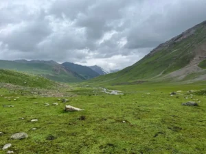 Trekkers hiking beside turquoise lake.